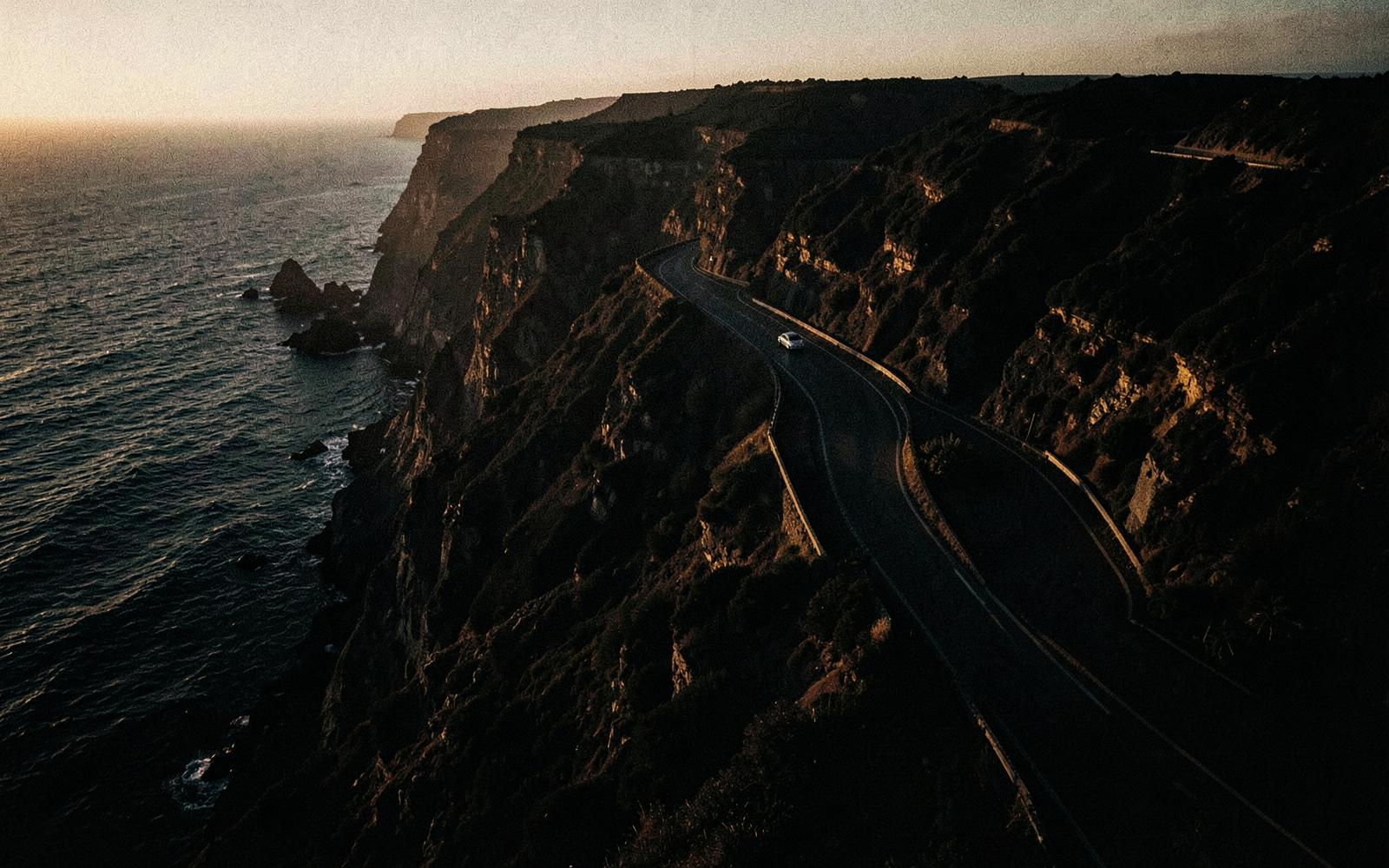 Coastal road winding along cliffs at golden hour